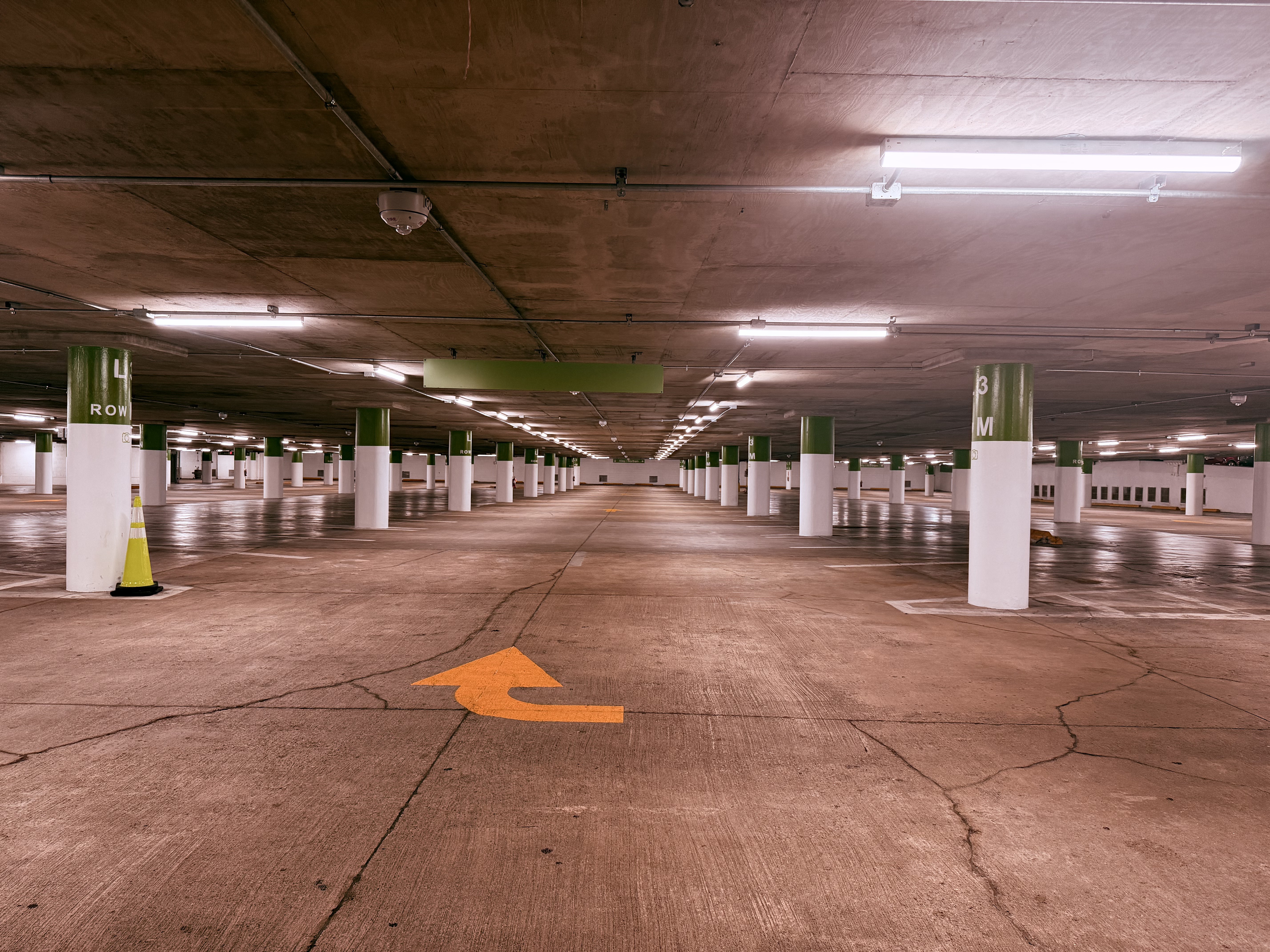 Empty parking garage, fluorescent lights receding into distance